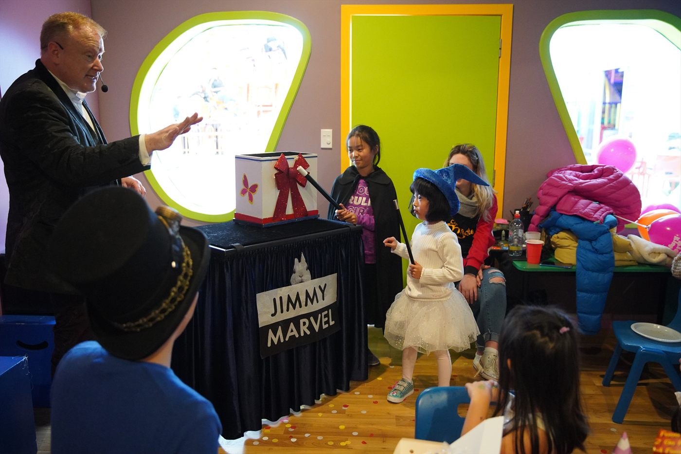Two children helping Jimmy Marvel perform a colourful magic routine